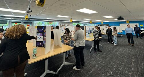 Attendees browsing student presentations at the Student Internship Program end-of-year showcase.